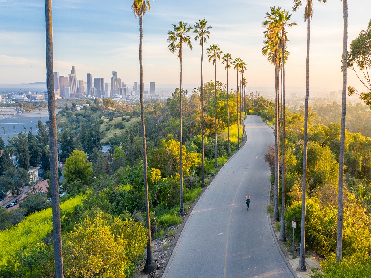 Drone shot of a woman walking down a street toward Downtown Los Angeles.