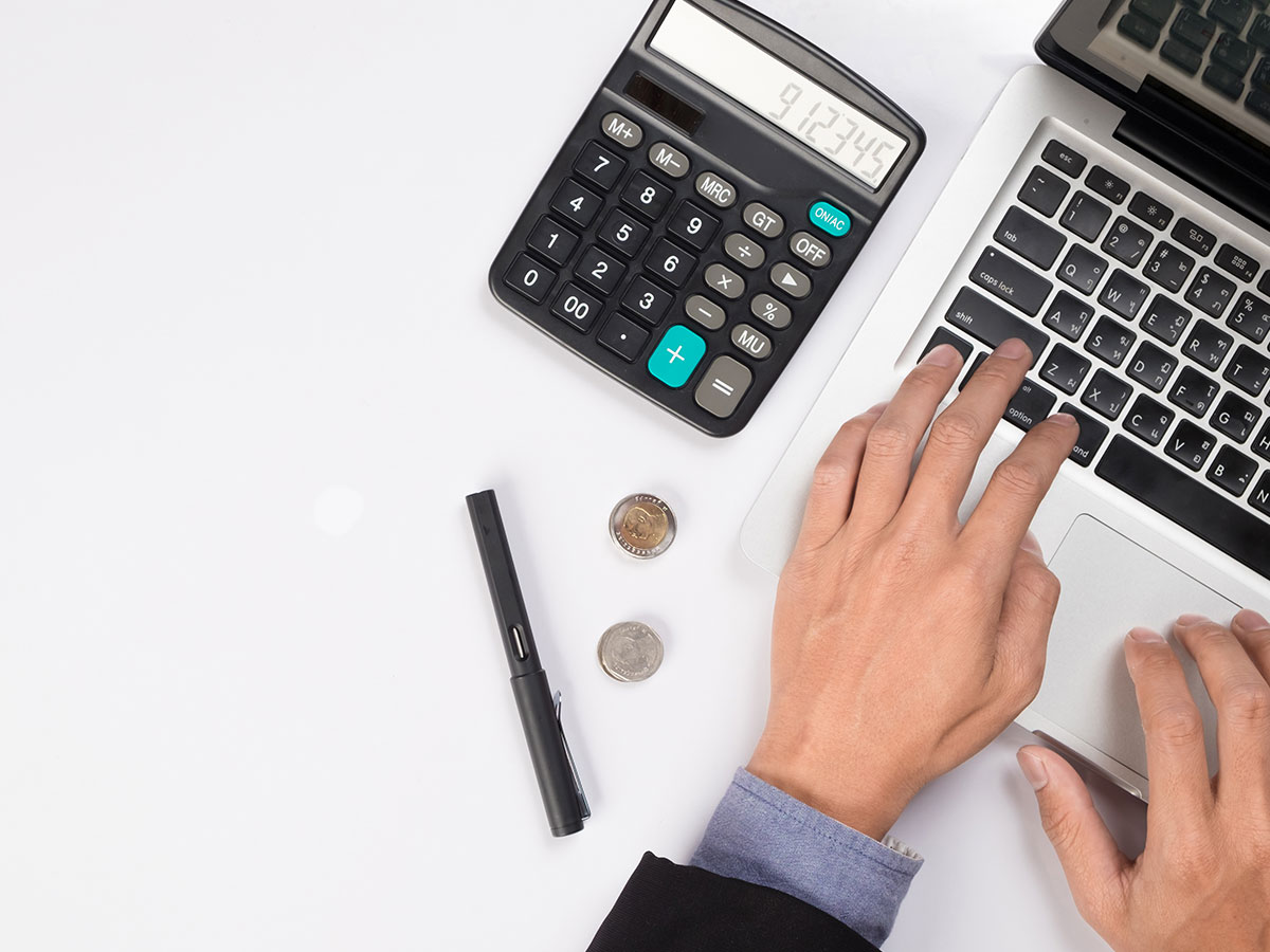 Male hands on computer with calculator